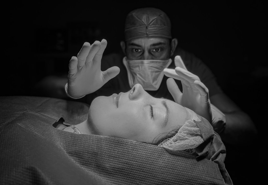 Dr. Jorge Barbachano studying a patient's nose before surgery, in black and white
